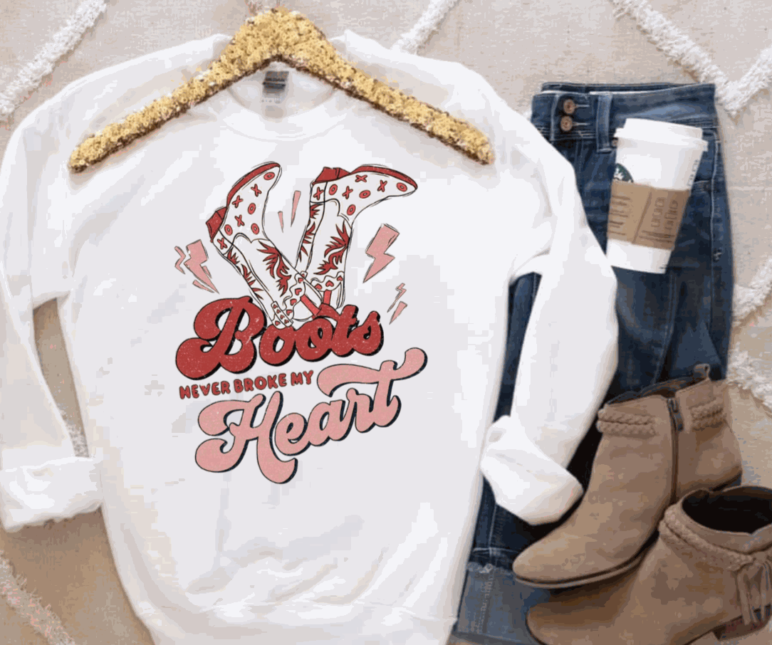 White Gildan sweatshirt with "Boots Never Broke My Heart" graphic, paired with jeans and tan boots.