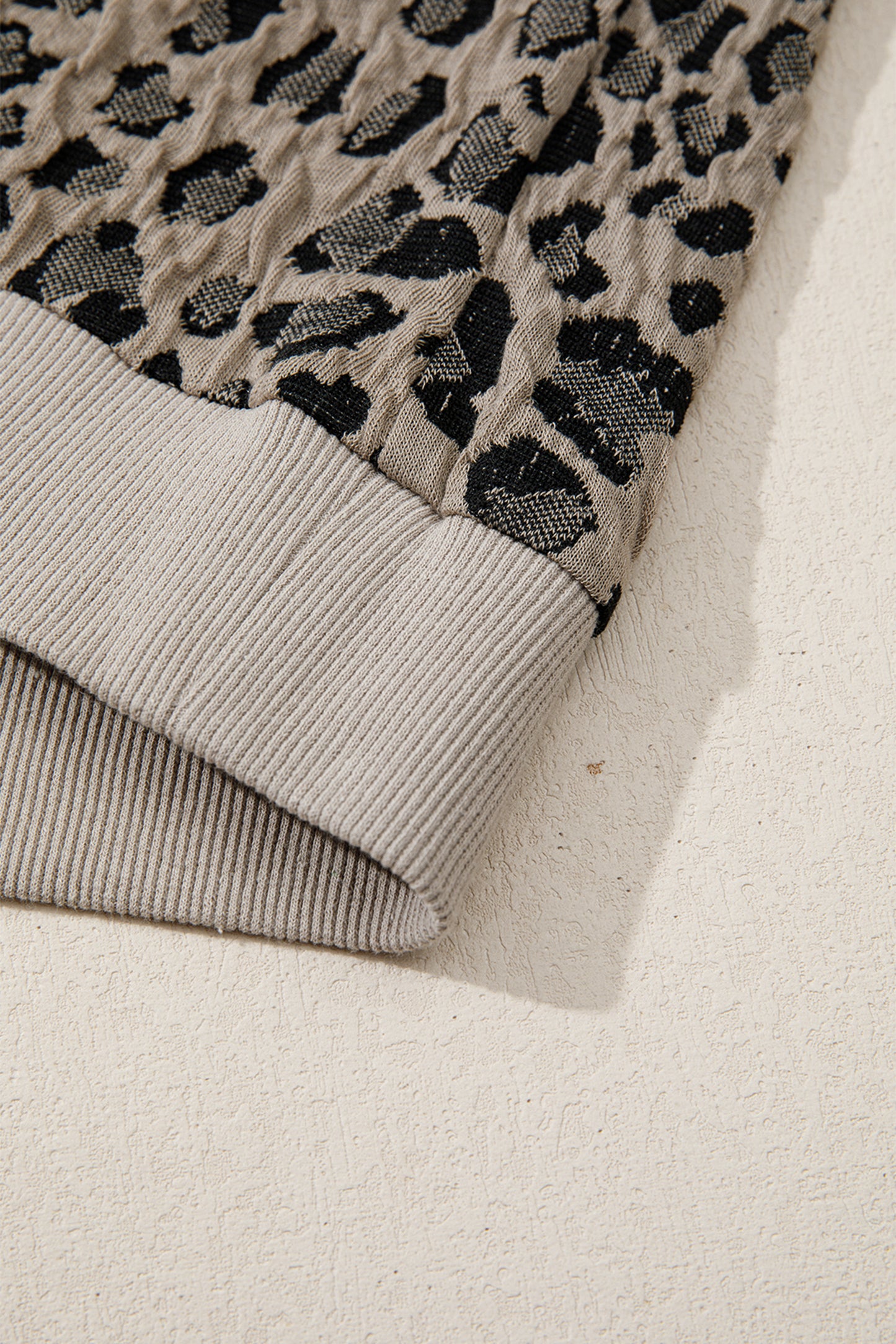 Beige leopard jacquard knit zip collar top - angled view on model showing cap sleeve and ribbed hem