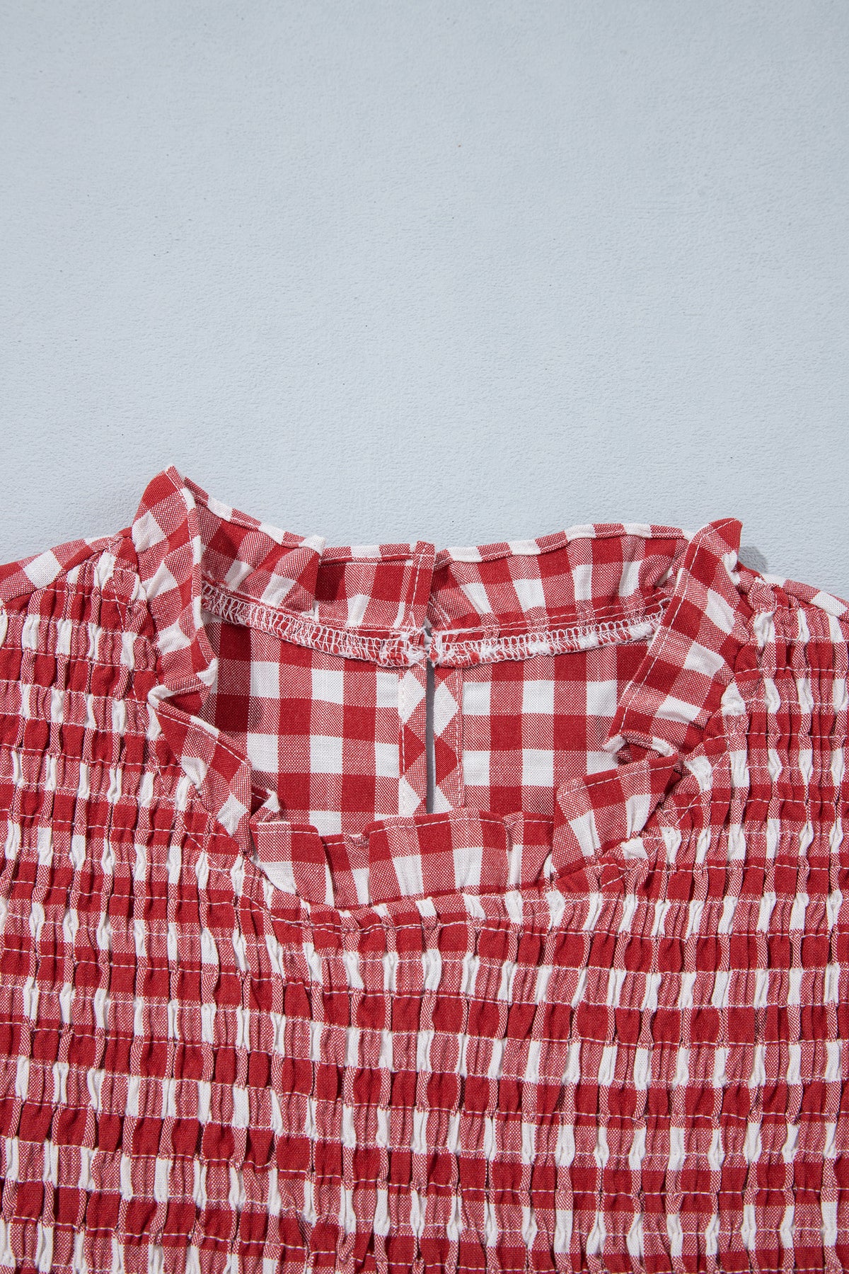 Ruffled neckline and shirred front detail of red plaid top