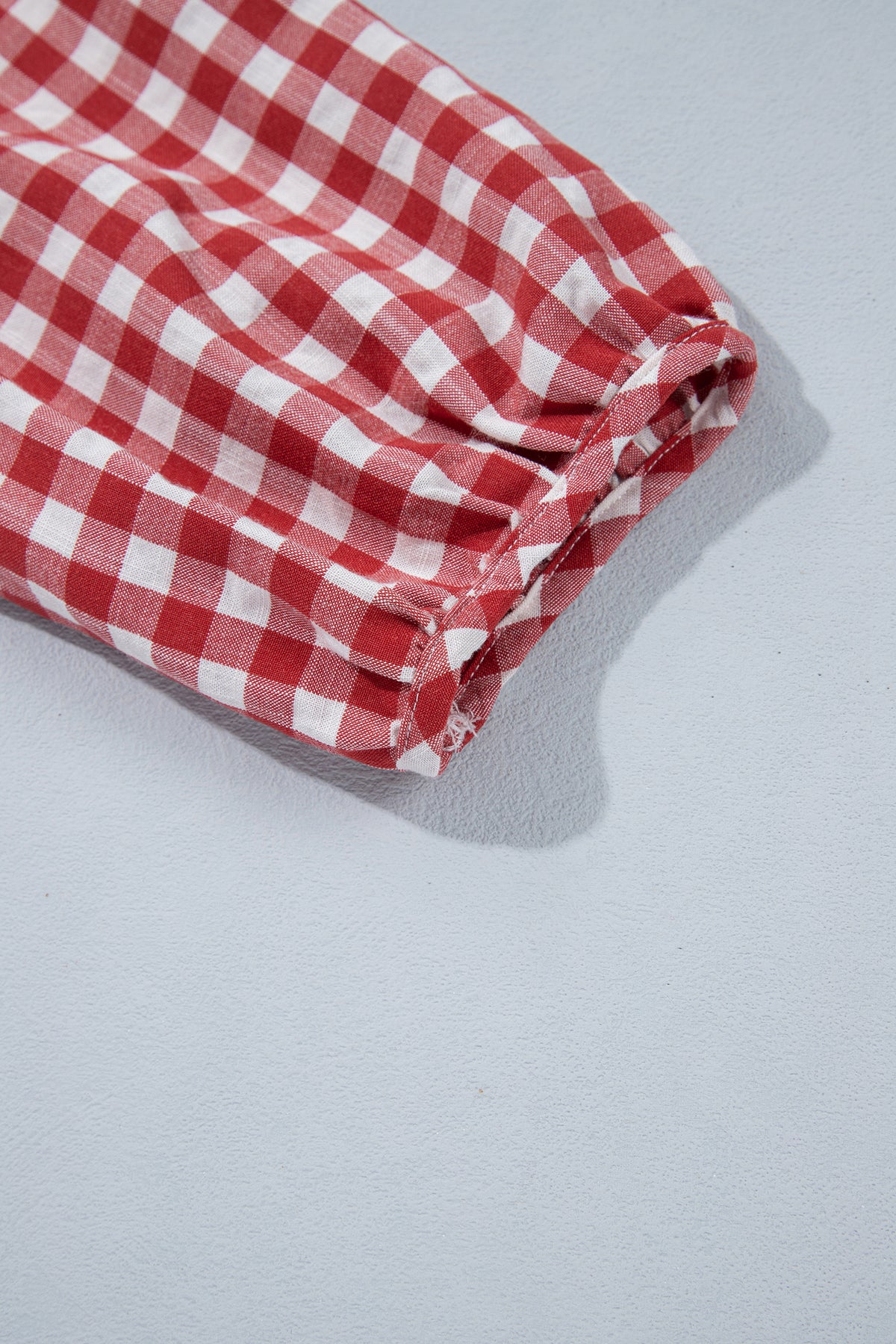 Full front view of red plaid shirred peplum top